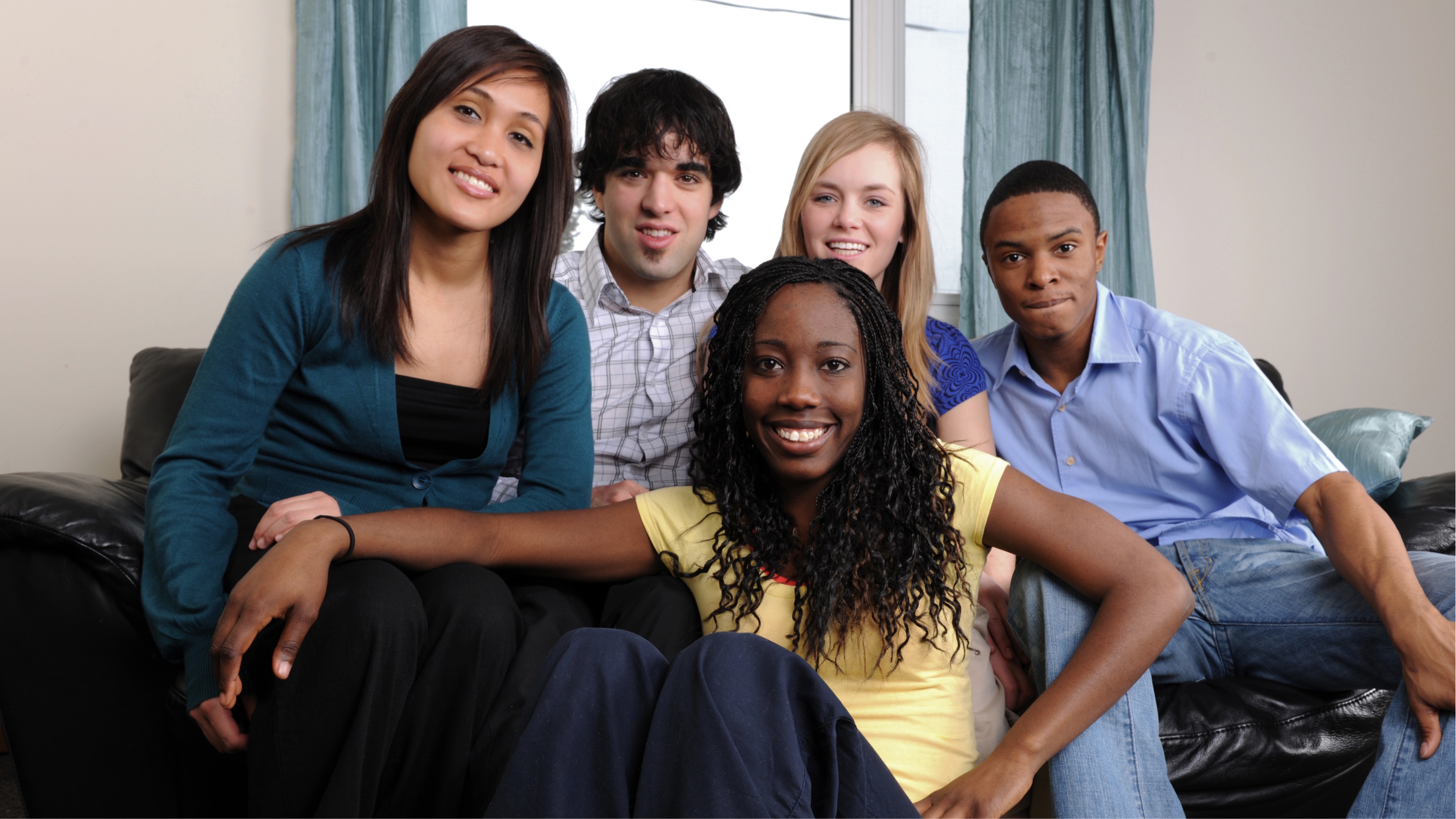 A diverse group of young adults smiling together on a couch