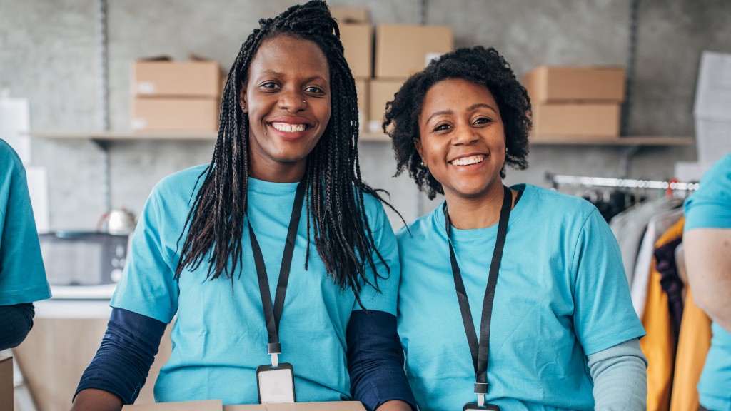 Two TIA volunteers smiling while sorting donations in a community warehouse.