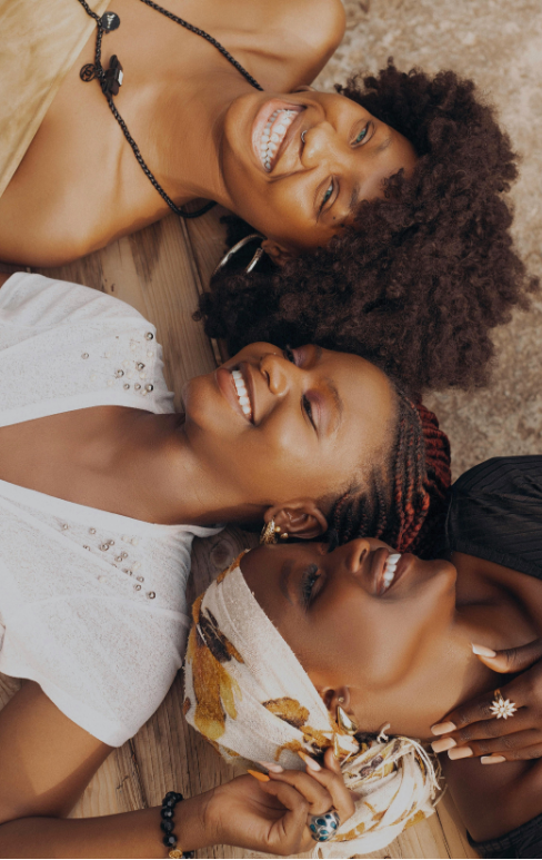Three women lying close together, smiling and laughing
